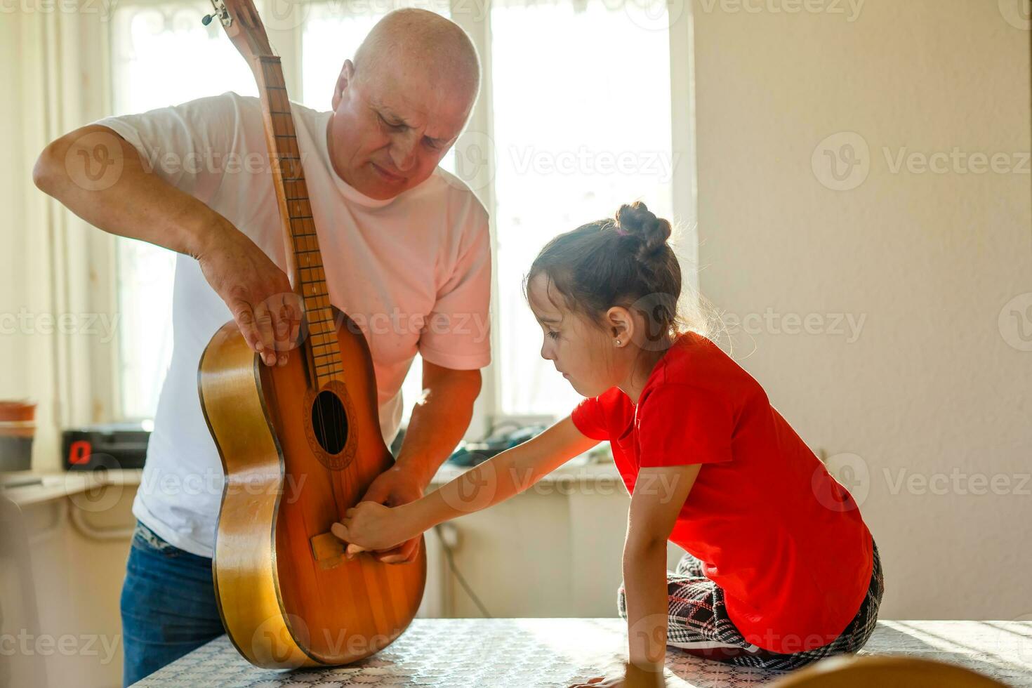 fermer homme main en changeant cordes sur le sien vieux acoustique guitare. photo