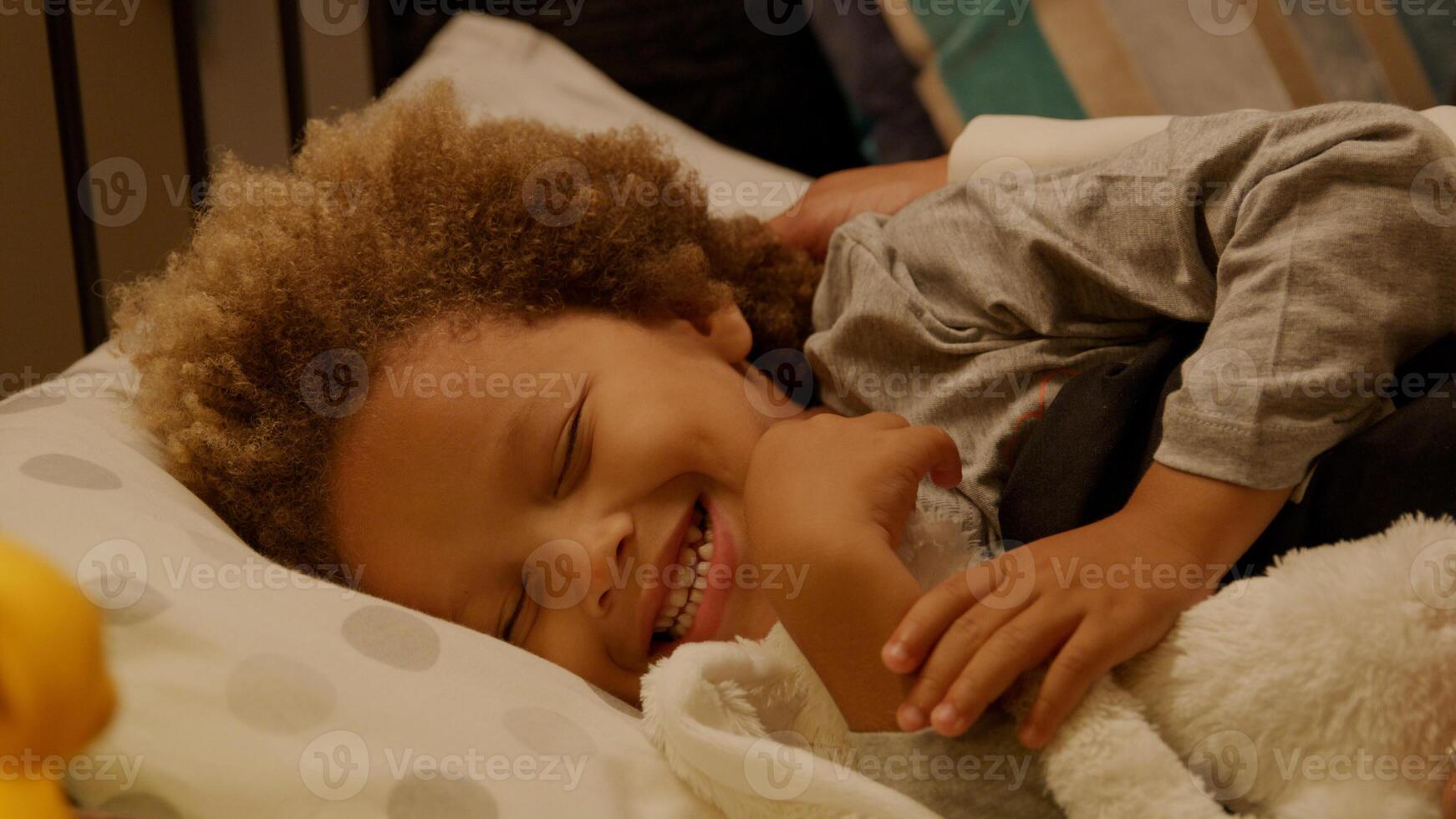 Jeune garçon mis au lit avec une peluche au coucher photo