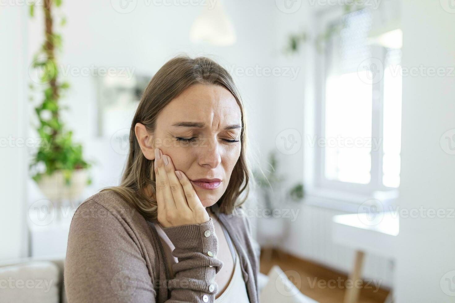 dent douleur et dentisterie. Jeune femme Souffrance de terrible fort les dents douleur, émouvant joue avec main. femelle sentiment douloureux mal aux dents. dentaire se soucier et santé concept. photo