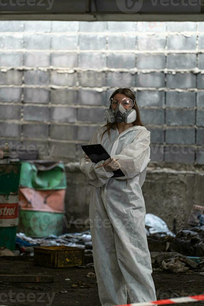 urgence la pollution usine concept. femelle chimiste portant ppe et gaz masque inspecter pétrole sur usine sol photo