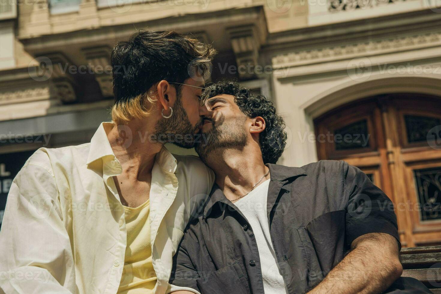 Hommes séance sur une banc dans le ville embrasser ang étreindre chaque autre photo