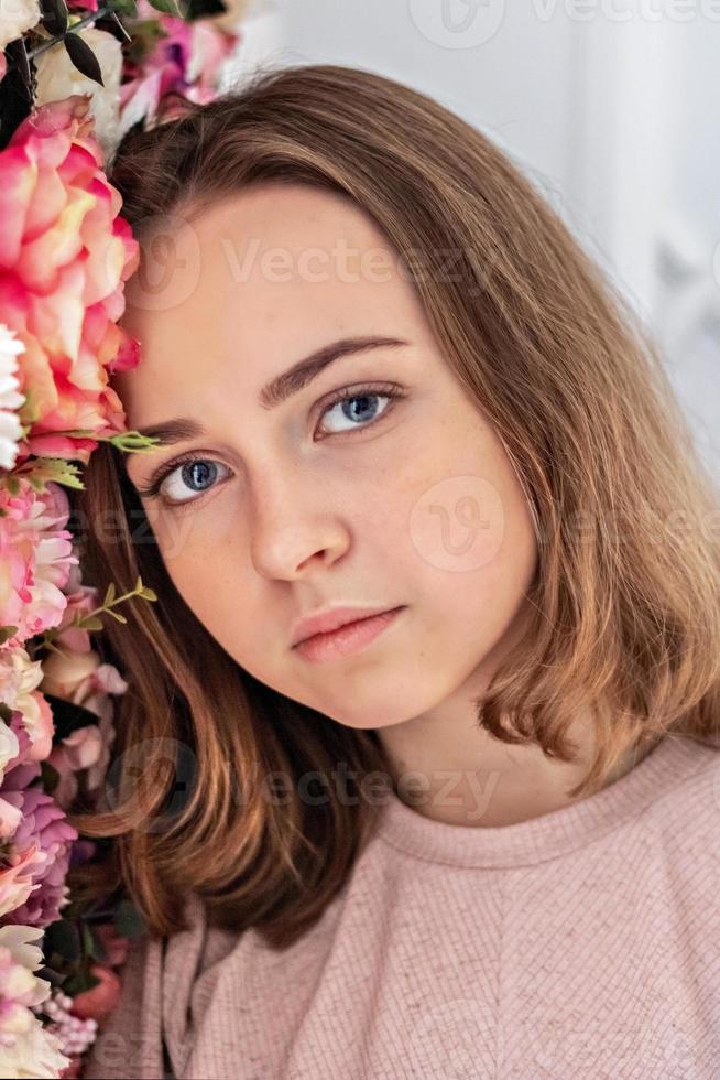 portrait d'une jeune fille au mur avec des fleurs. photo