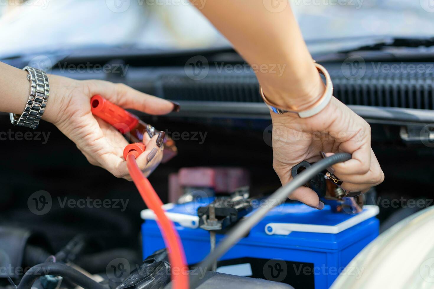 gros plan et mise au point sélective d'un mécanicien automobile tenant un cavalier de câbles électriques de batterie pour charger la batterie de voiture, concept de machine de moteur de voiture de services photo