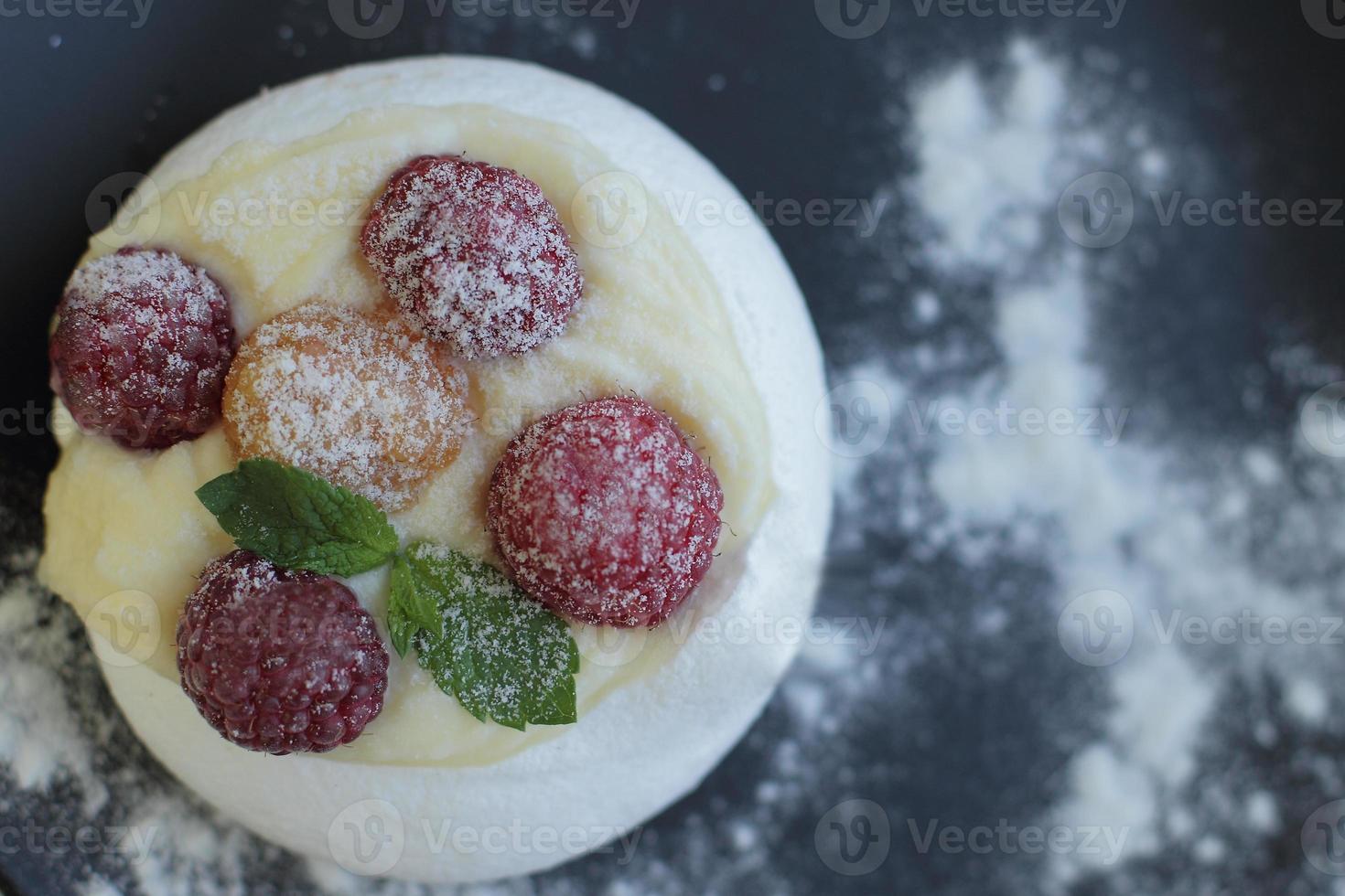 gâteau de meringue blanche avec des framboises jaunes et rouges sur une plaque noire place pour le texte photo