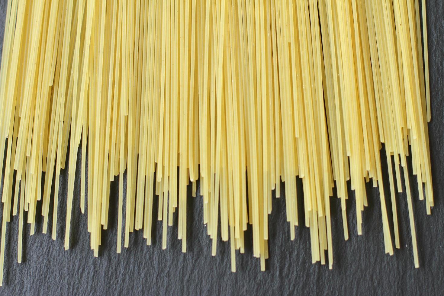 spaghettis frais crus, jaune mince sur fond noir photo