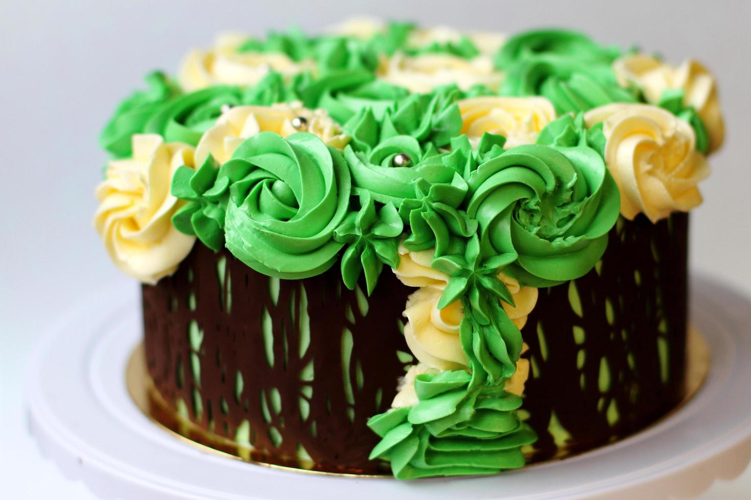 magnifique gâteau fait maison recouvert de roses jaunes et vertes à base de crème au beurre, cadre en chocolat, glaçage sur fond blanc photo