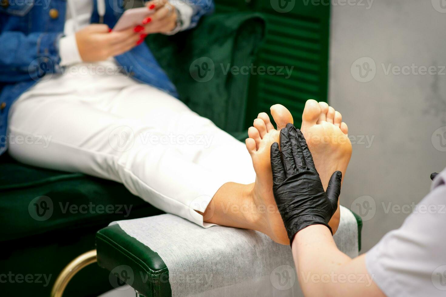 hydratant le pieds. mains de pédicure Maître dans noir gants se soucier à propos femelle pieds. pied massage. pédicure beauté salon concept. photo