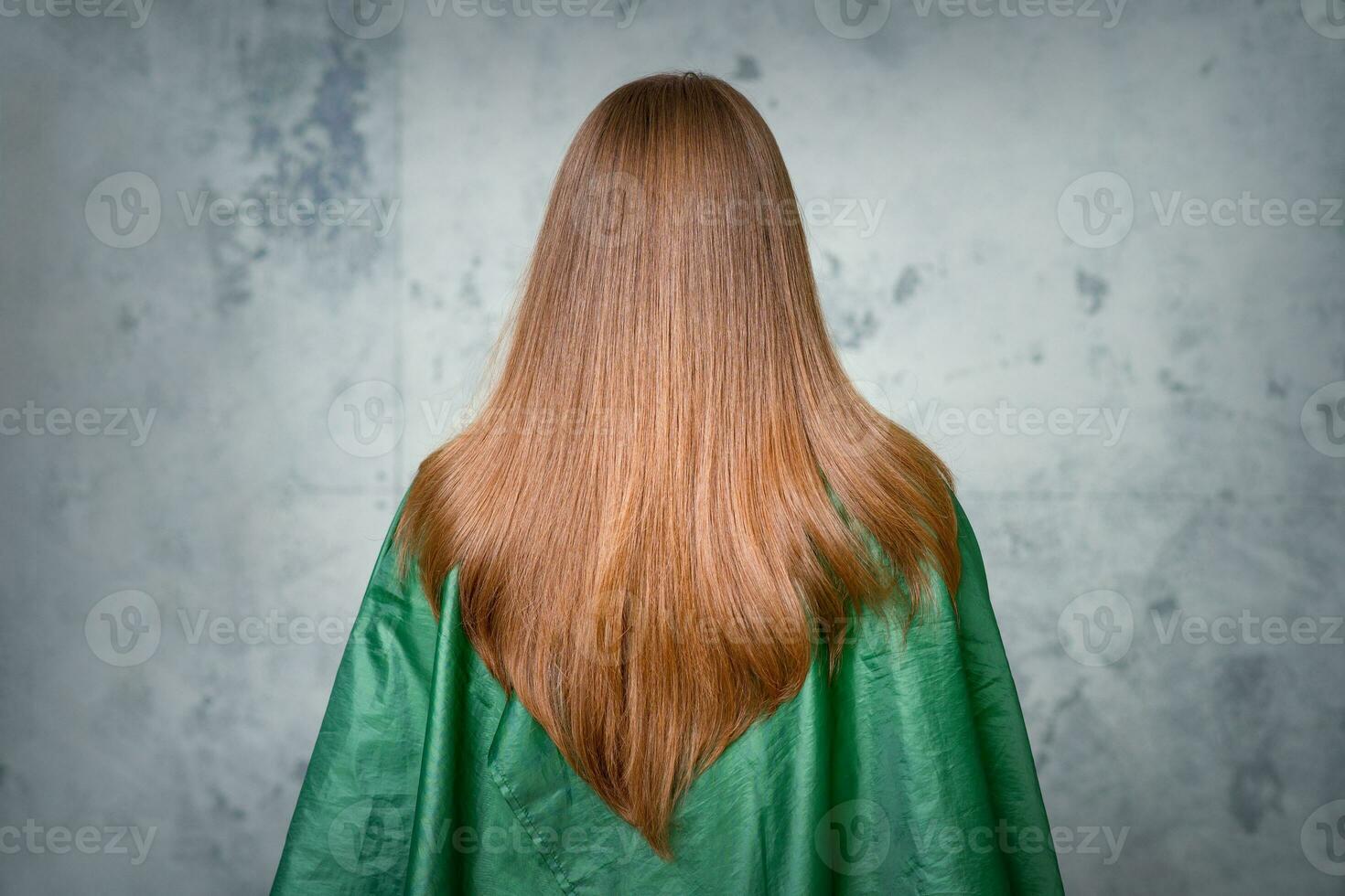 arrière vue de une femme avec longue marron cheveux contre une gris Contexte. photo