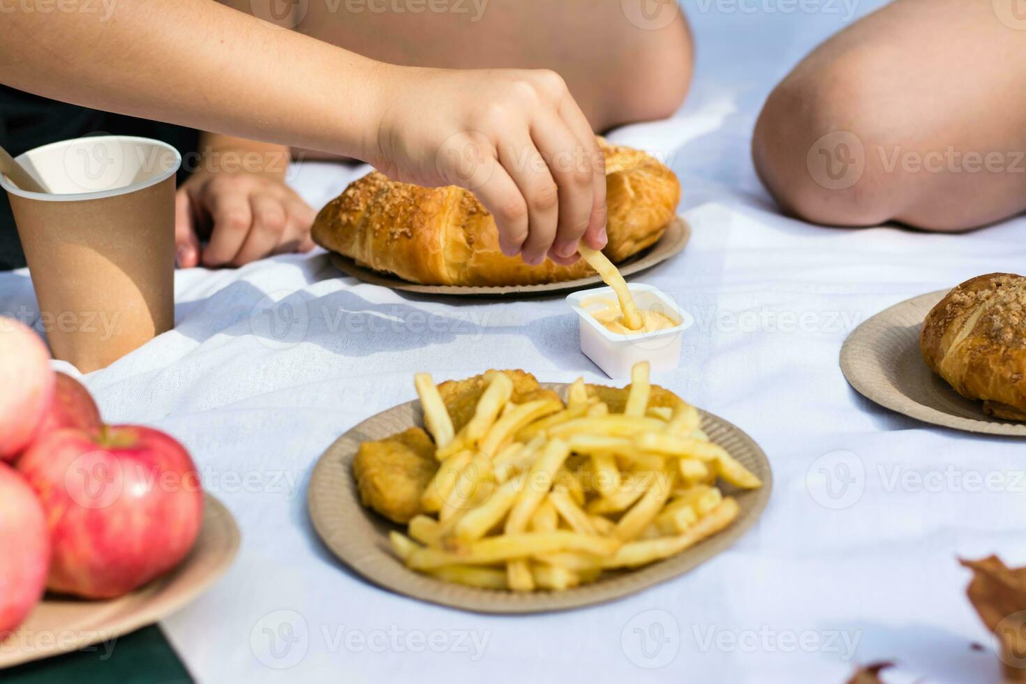 deux écolières manger frites avec sauce à une pique-nique dans le parc. respectueux de la nature jetable vaisselle. école repas photo