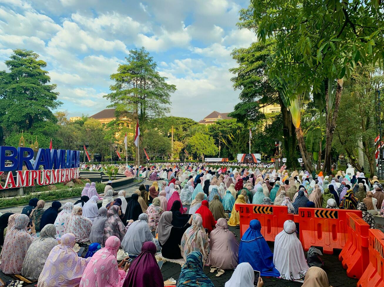 sholat idiot fitri. indonésien musulman communauté sont Faire eid Al fitr prière dans Extérieur zone. sholat idiot adha dans Université champ avec mots veux dire indépendant Université photo