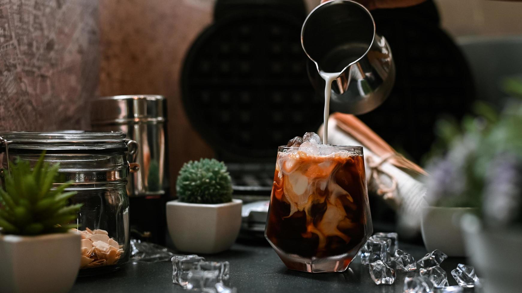 barista versant du lait dans un verre de café glacé photo