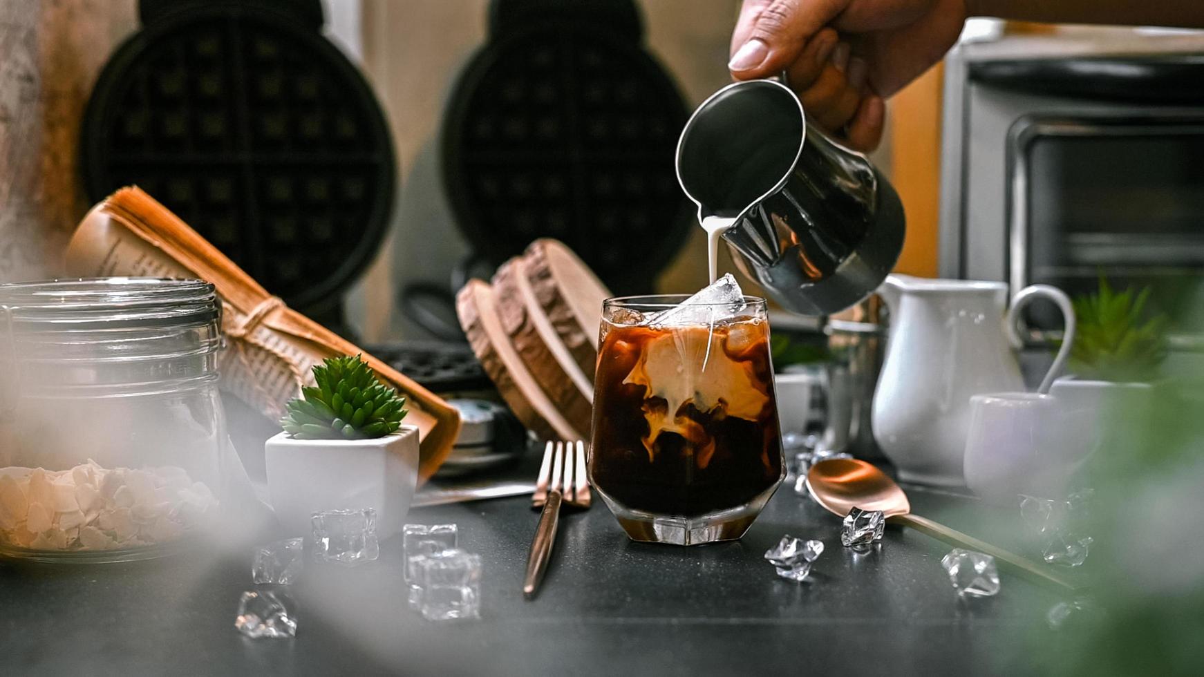 barista versant du lait dans un verre de café glacé photo