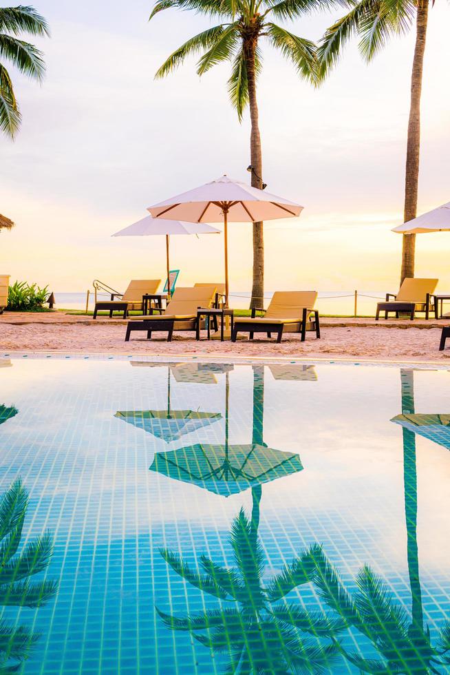 Parapluie et chaise autour de la piscine de l'hôtel resort avec lever de soleil le matin photo