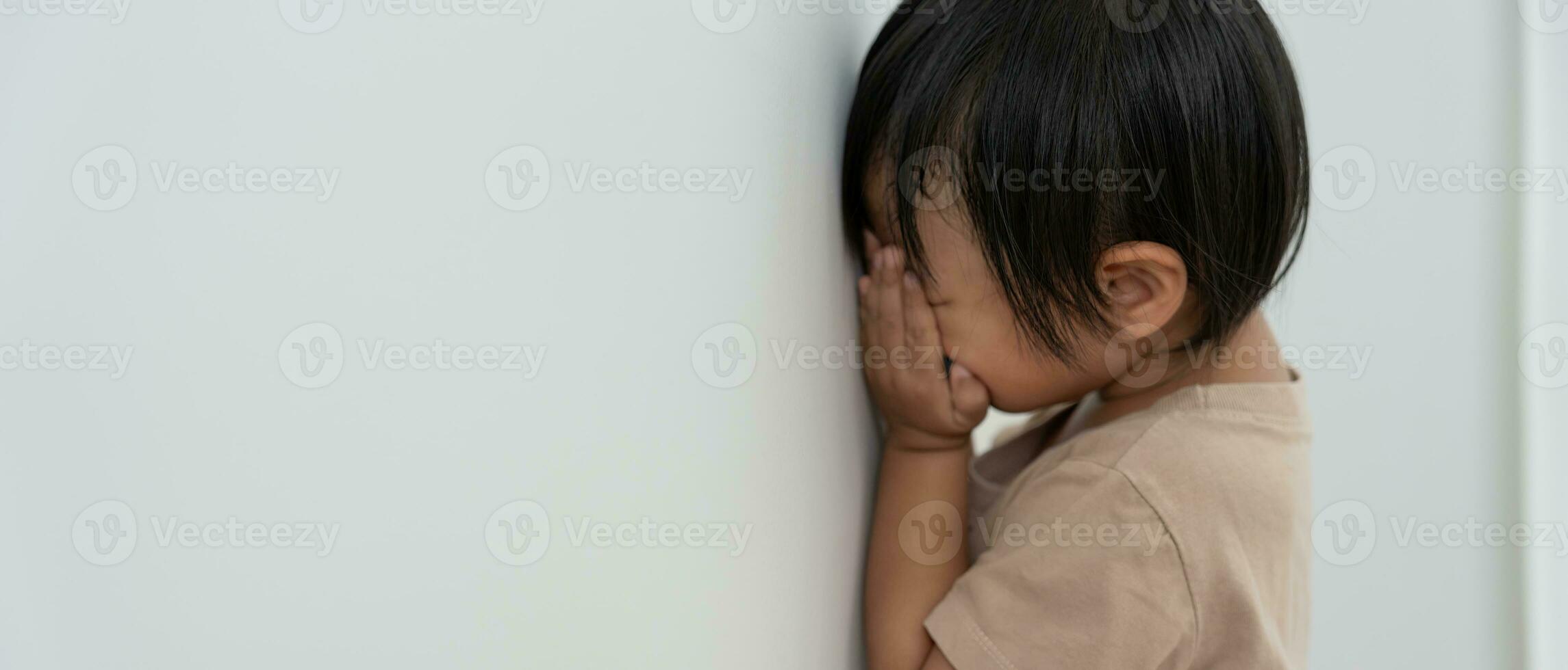 peu asiatique les enfants enfant fille couvrant le sien yeux avec mains, en jouant cacher et chercher permanent suivant une mur loger, adorable enfant ayant amusement dans le maison. content famille avoir amusement avec enfants, activité photo