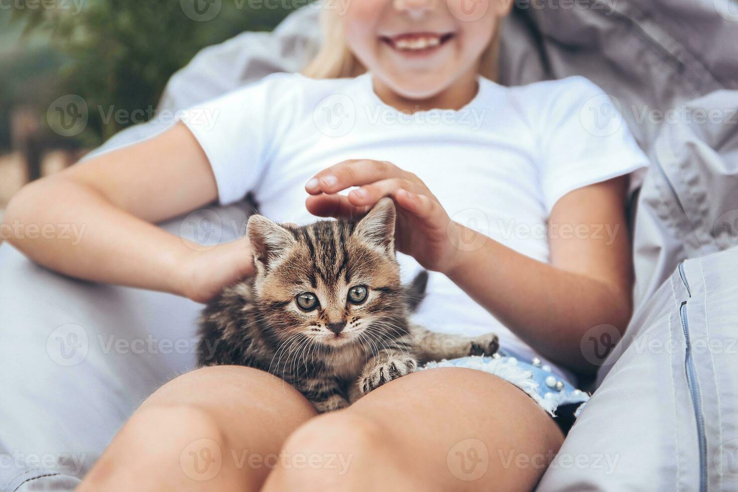 une enfant détient une petit chaton et coups il. tonique image. photo