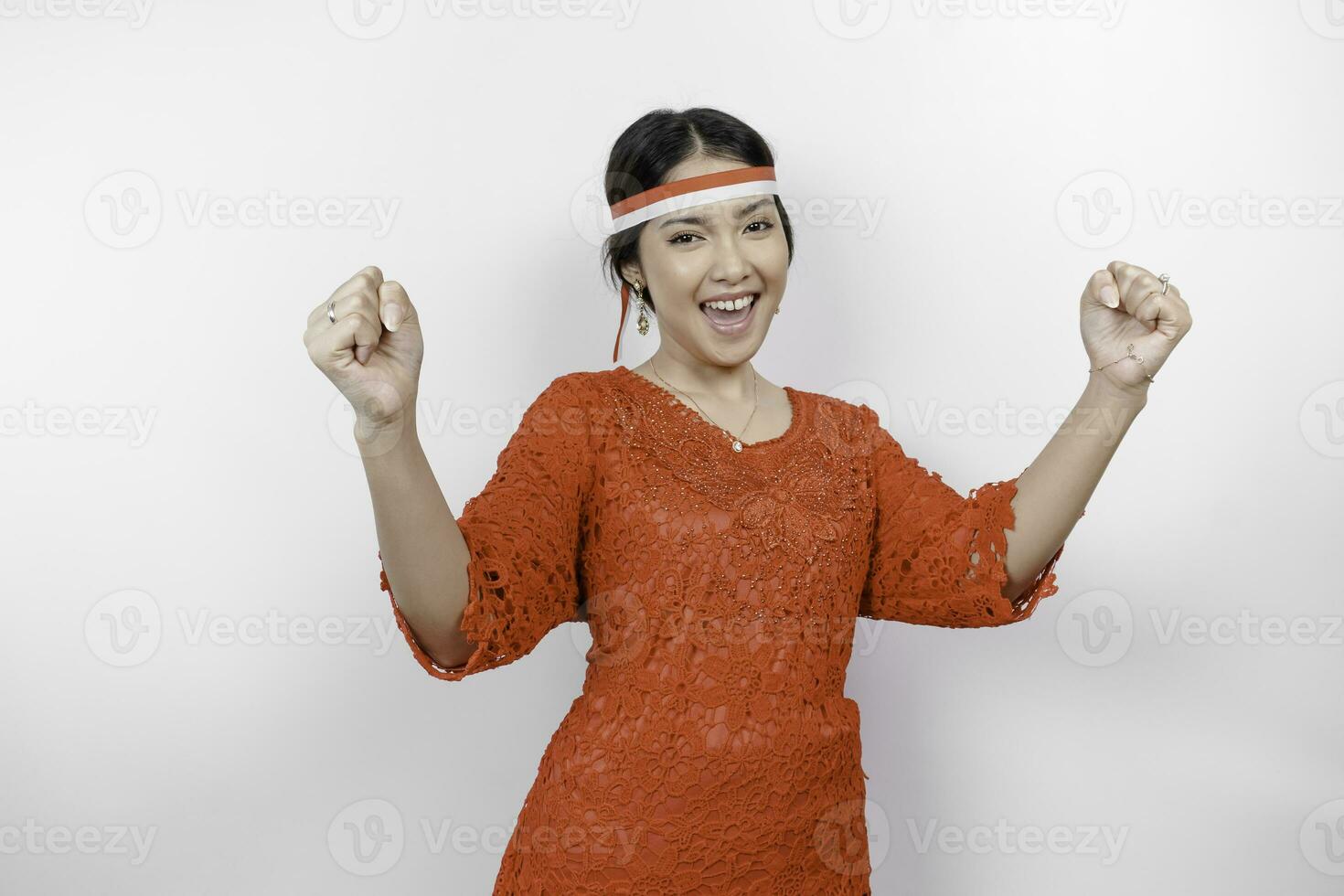 une Jeune asiatique femme avec une content réussi expression portant rouge kebaya et Bandeau isolé par blanc Contexte. l'indonésie indépendance journée concept. photo