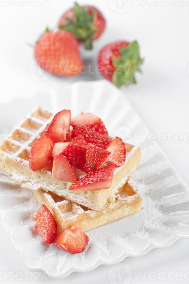 gaufres belges avec du sucre en poudre et des fraises sur une plaque en céramique sur un tableau blanc. photo