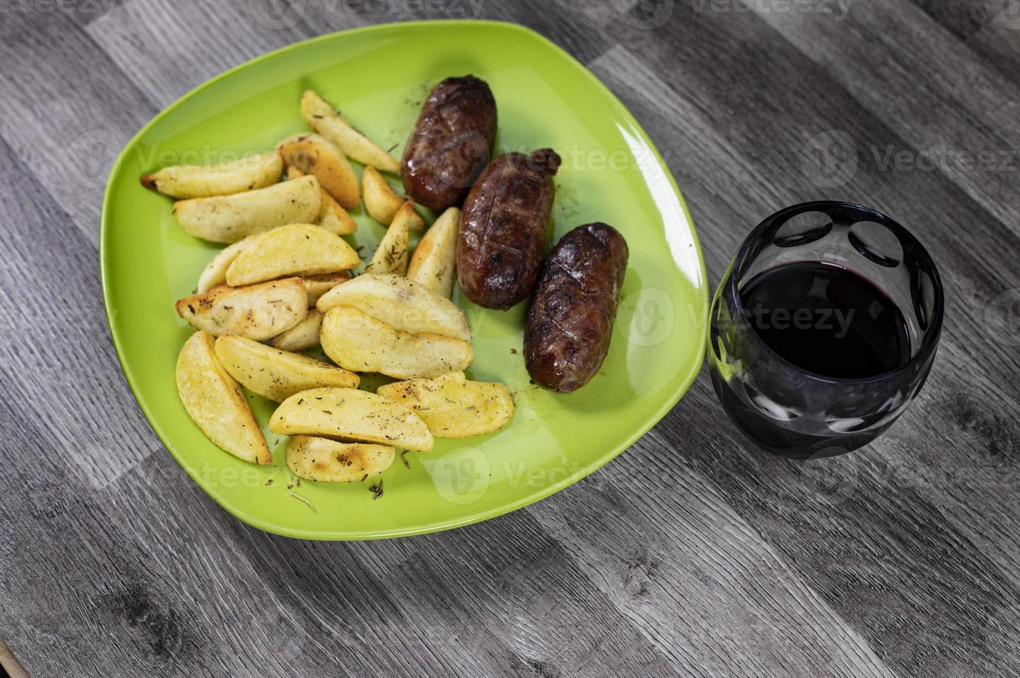 assiette saucisses pommes de terre et un verre de vin photo