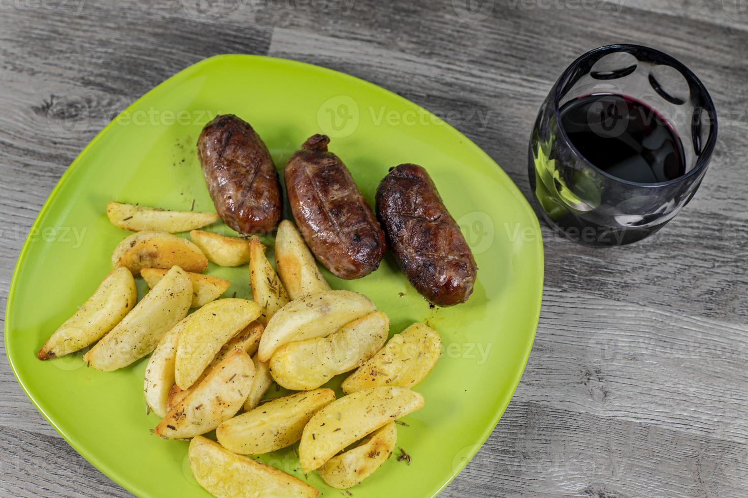 assiette saucisses pommes de terre et un verre de vin photo