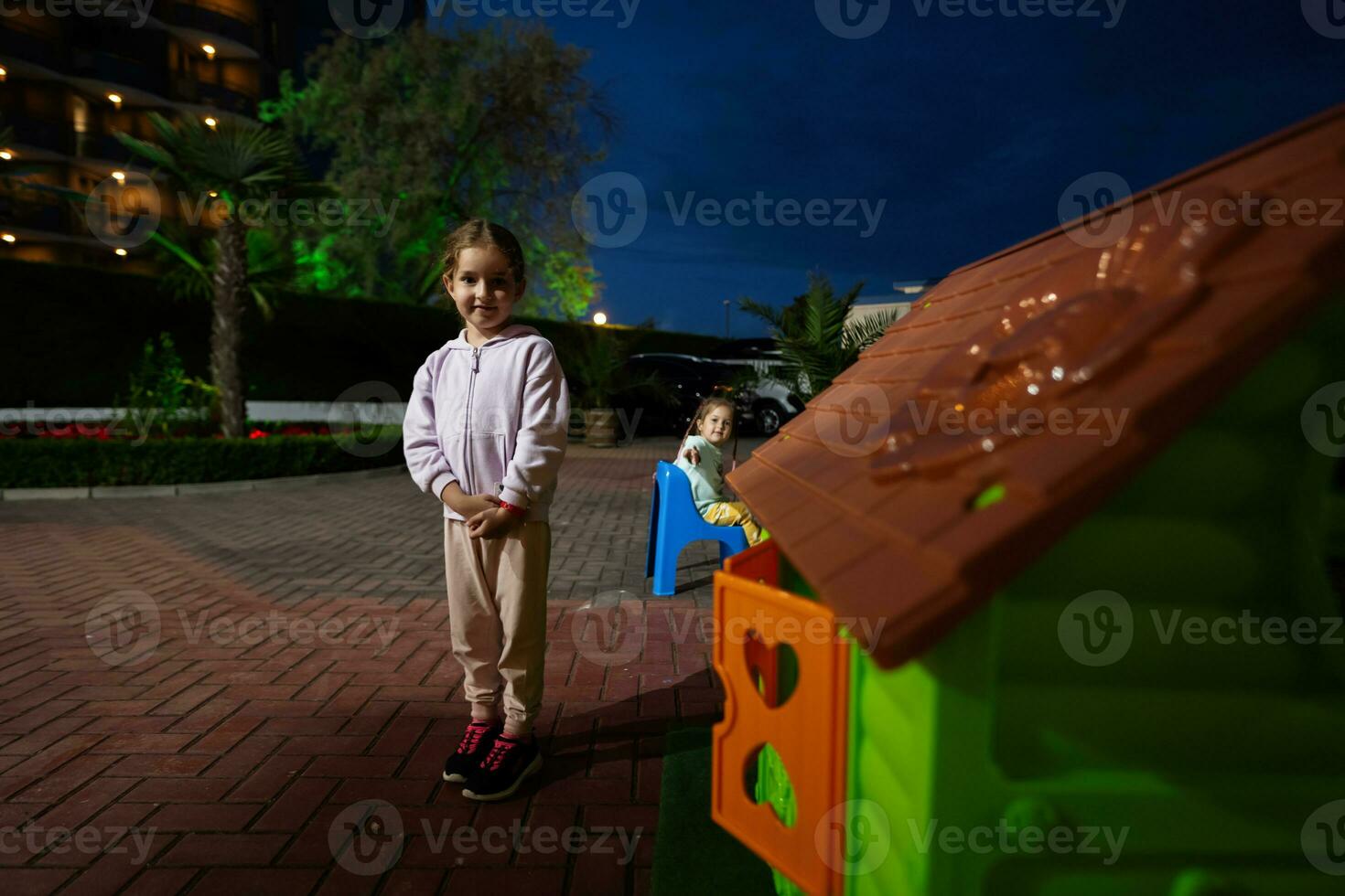 mignonne peu fille en jouant avec jouet maison dans le parc à nuit. photo