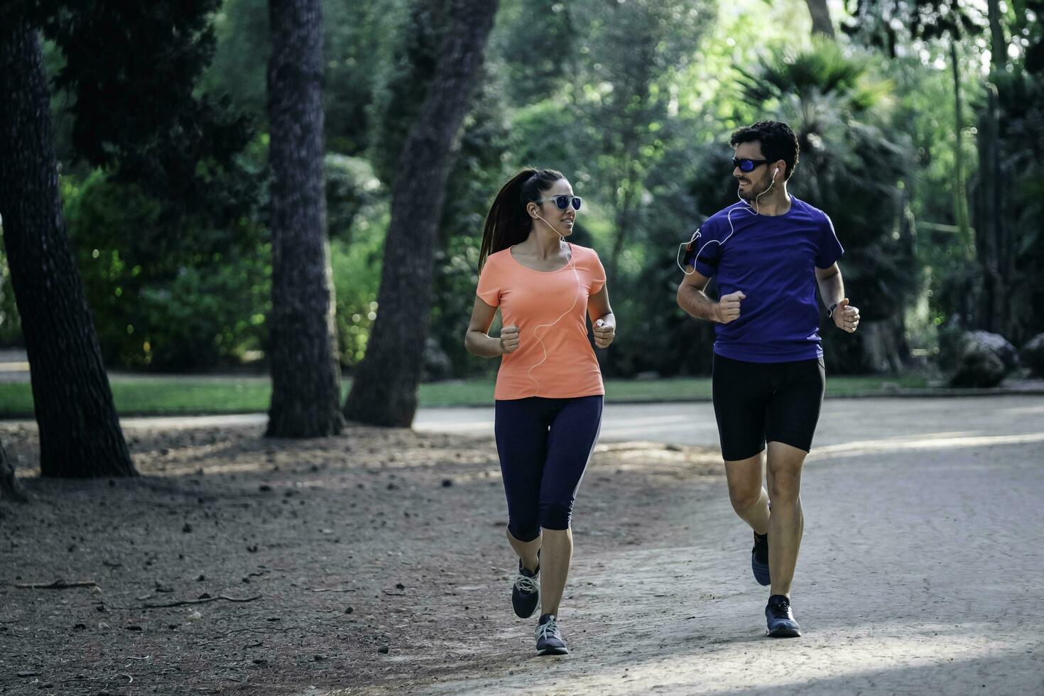 Jeune couple fonctionnement par le parc et écoute à musique. en bonne santé vivant concept. photo