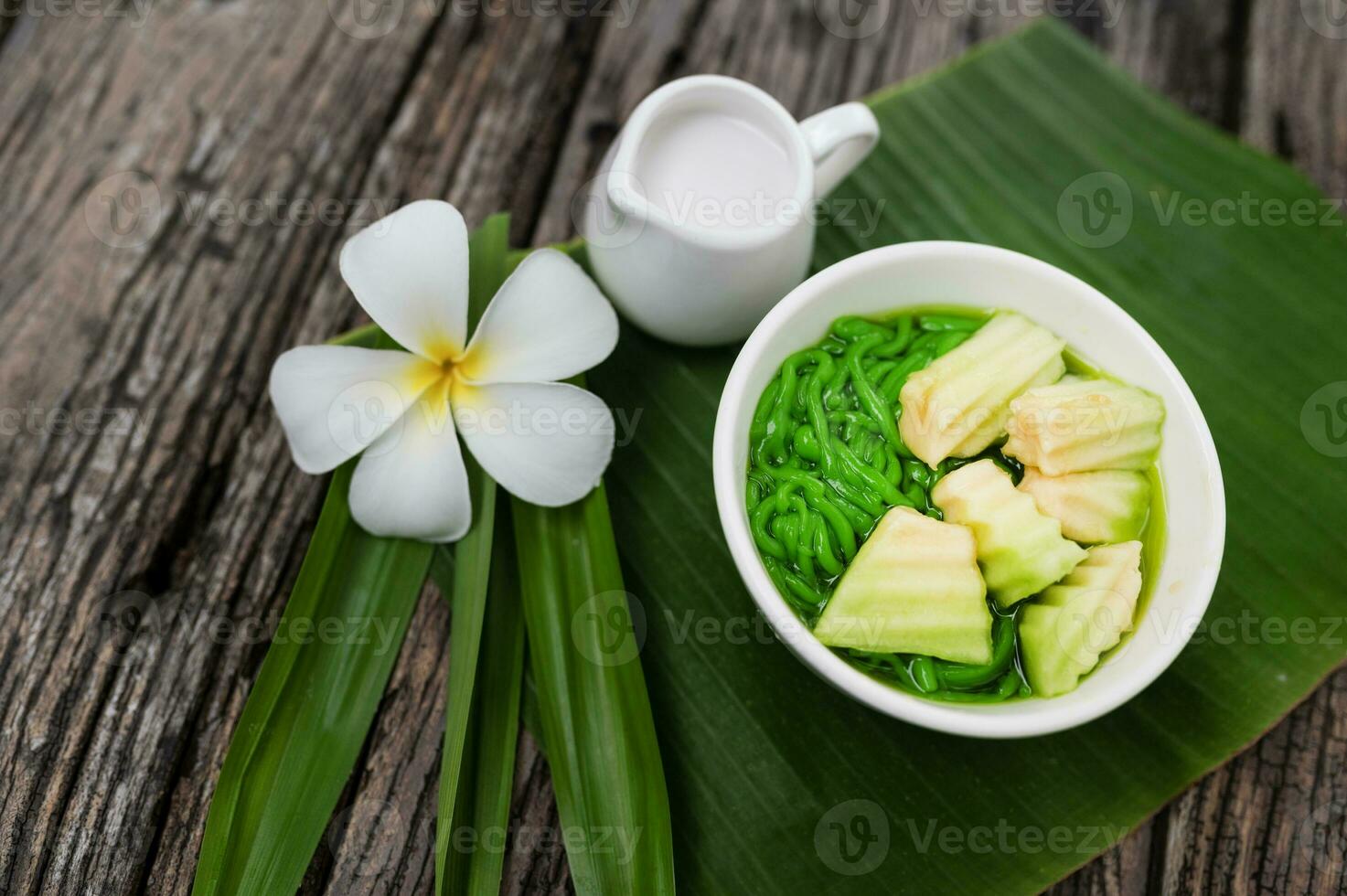 loger chong parfumé pandan riz égouttage dans noix de coco Lait dans une en bois bol sur une vert banane feuille Contexte. ou loger chong mixte avec thaïlandais melons asiatique thaïlandais desserts photo