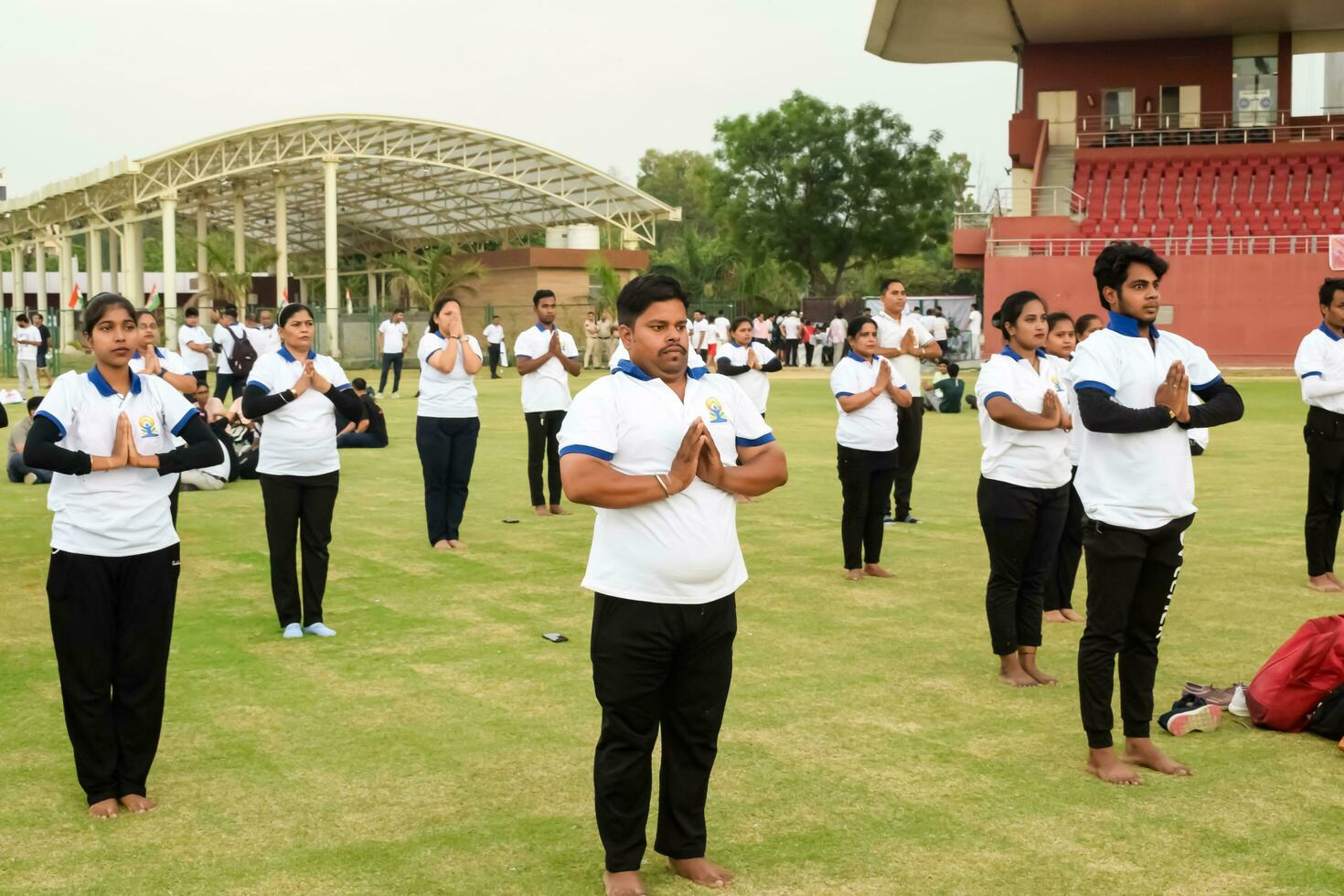 Nouveau Delhi, Inde, juin 21, 2023 - groupe yoga exercice session pour gens à yamuna des sports complexe dans delhi sur international yoga jour, gros groupe de adultes assister yoga classe dans criquet stade photo