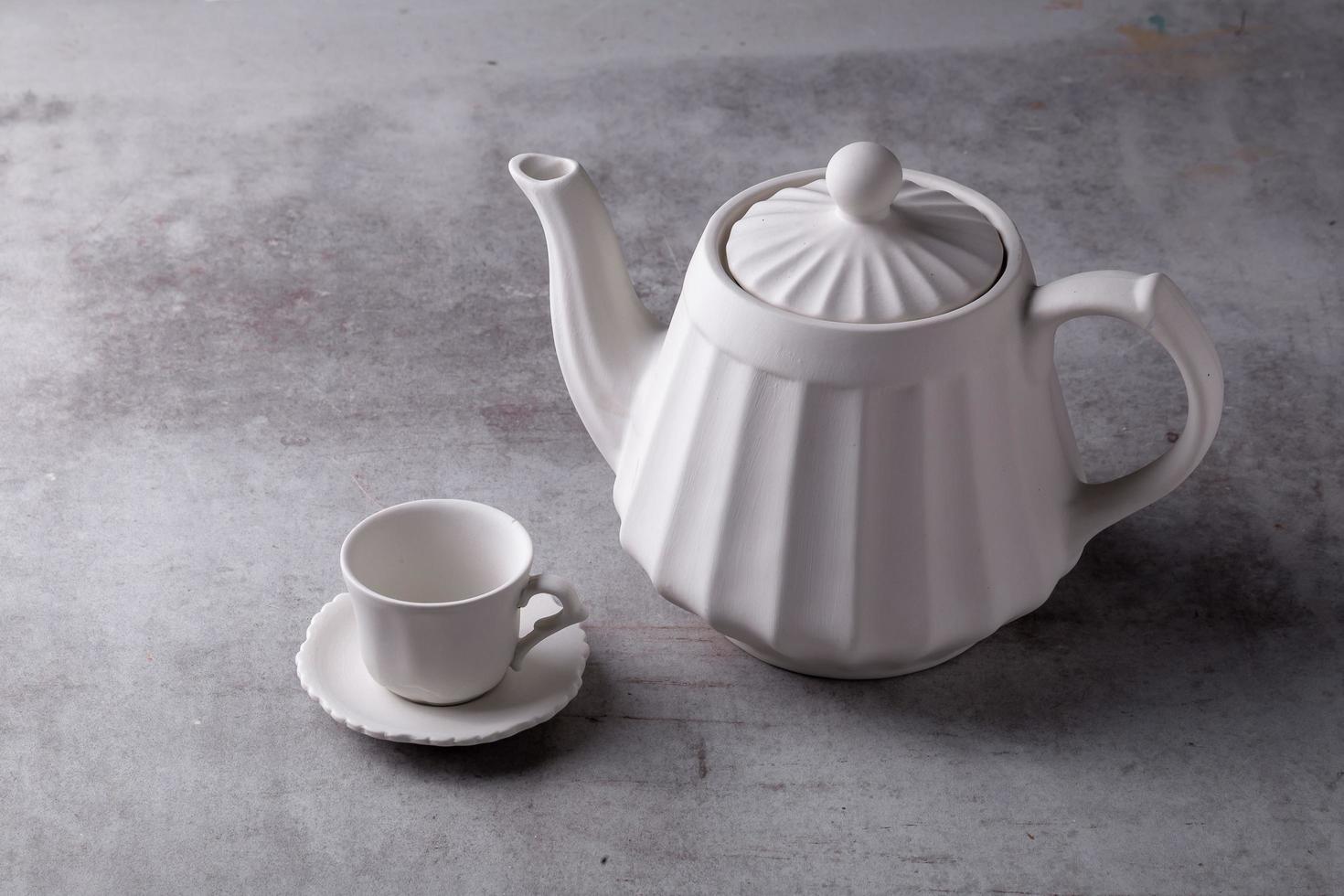 tasse et soucoupe de crémier de théière sur le conseil de ciment photo