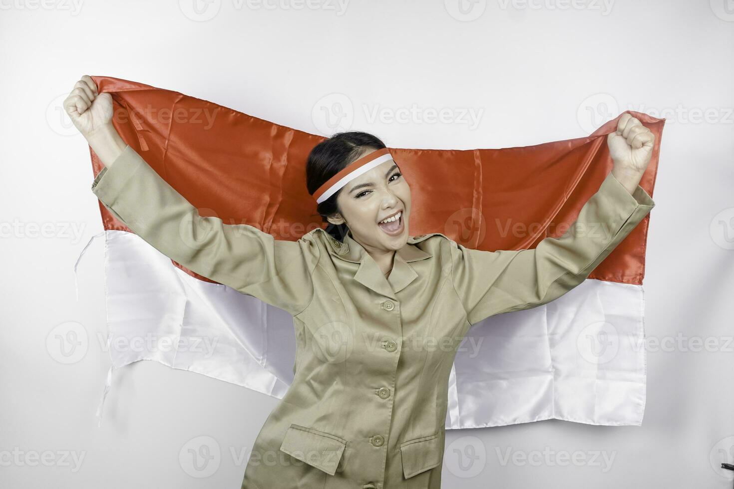 souriant gouvernement ouvrier femme en portant l'indonésie drapeau isolé par blanc Contexte. pns portant kaki uniforme. l'indonésie indépendance journée concept. photo