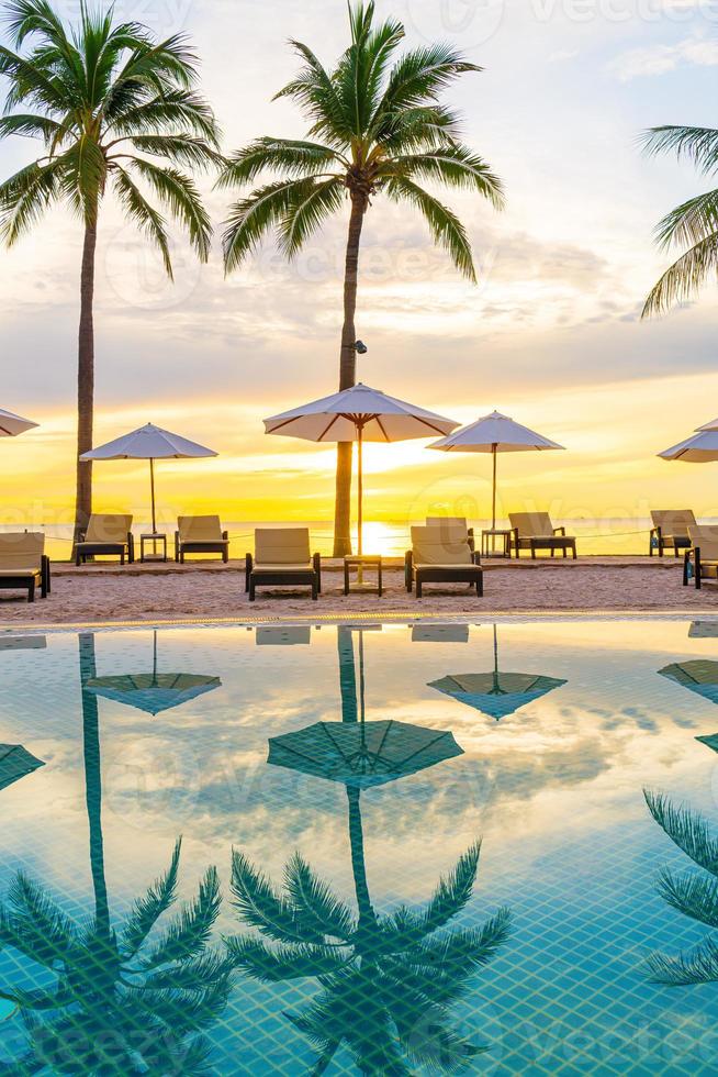 Parapluie et chaise autour de la piscine de l'hôtel resort avec lever de soleil le matin photo