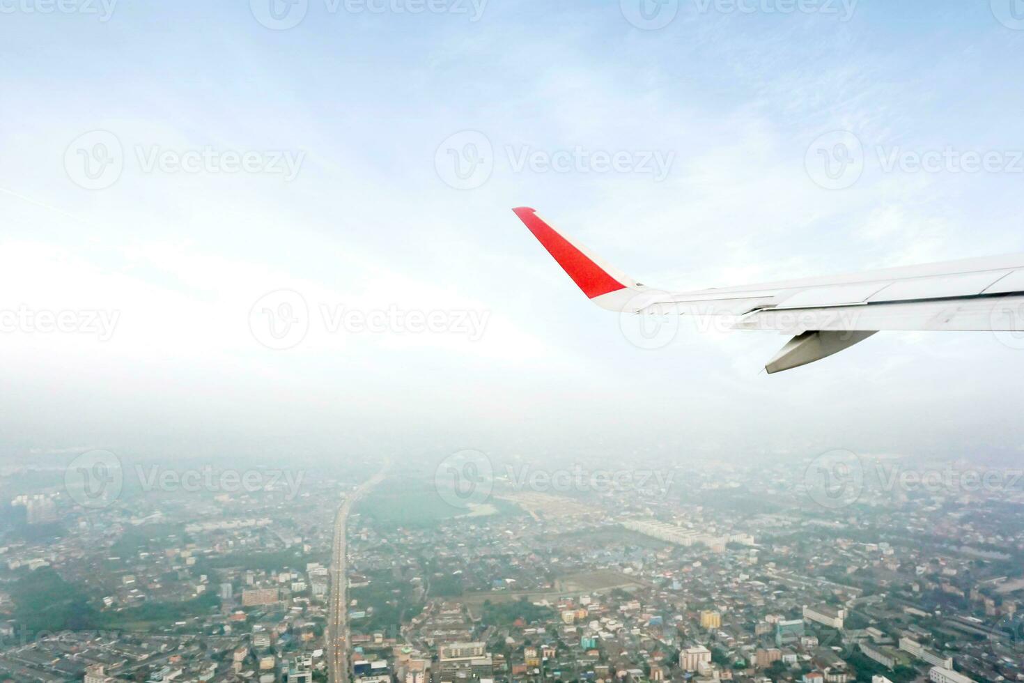 à l'extérieur avion fenêtre vue avec avion aile étant décollage sur bleu ciel et plus haute de paysage vue Contexte. photo