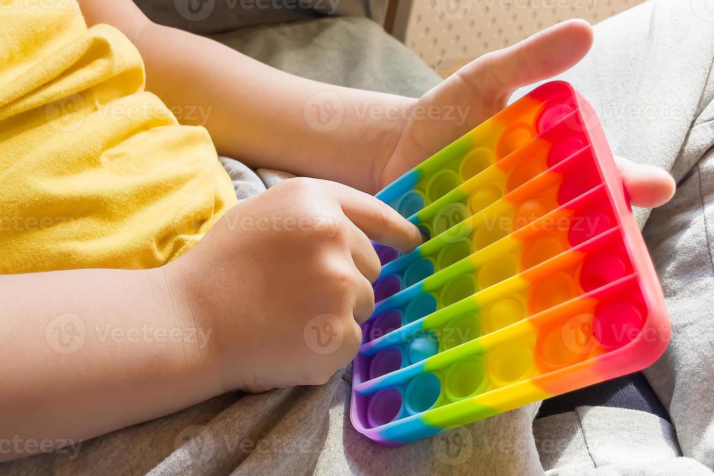 Jouet sensoriel anti-stress coloré push pop it dans les mains des enfants photo