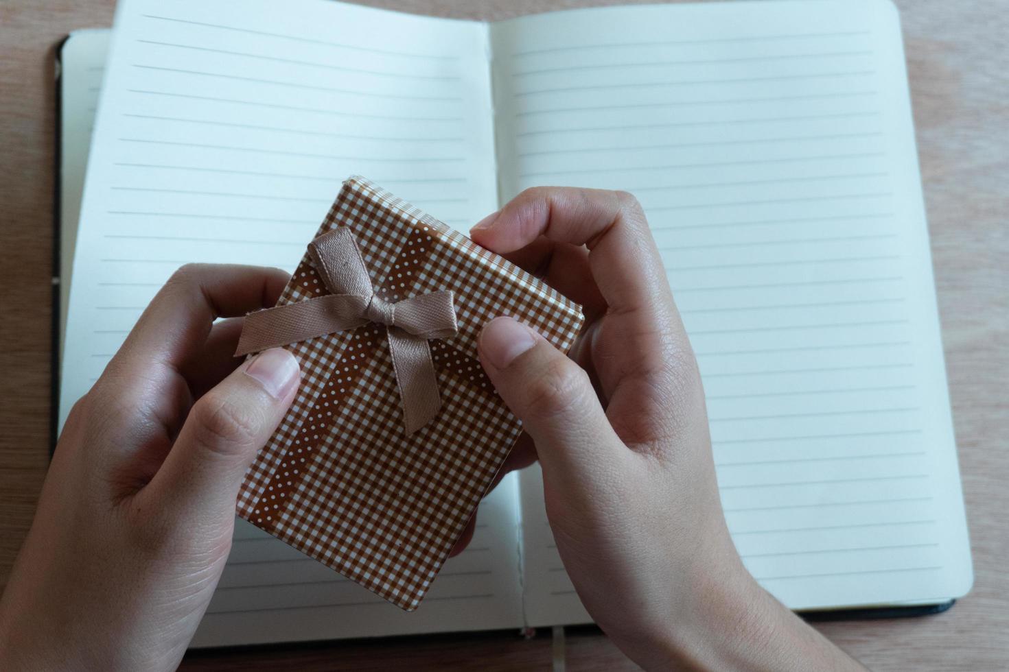 gros plan de mains féminines tenant un petit cadeau. petit cadeau entre les mains d'une femme d'intérieur. photo