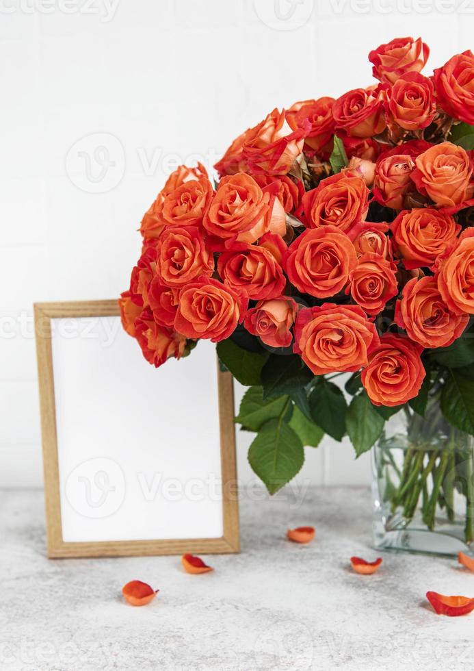 roses rouges dans un vase en verre avec un cadre photo vide