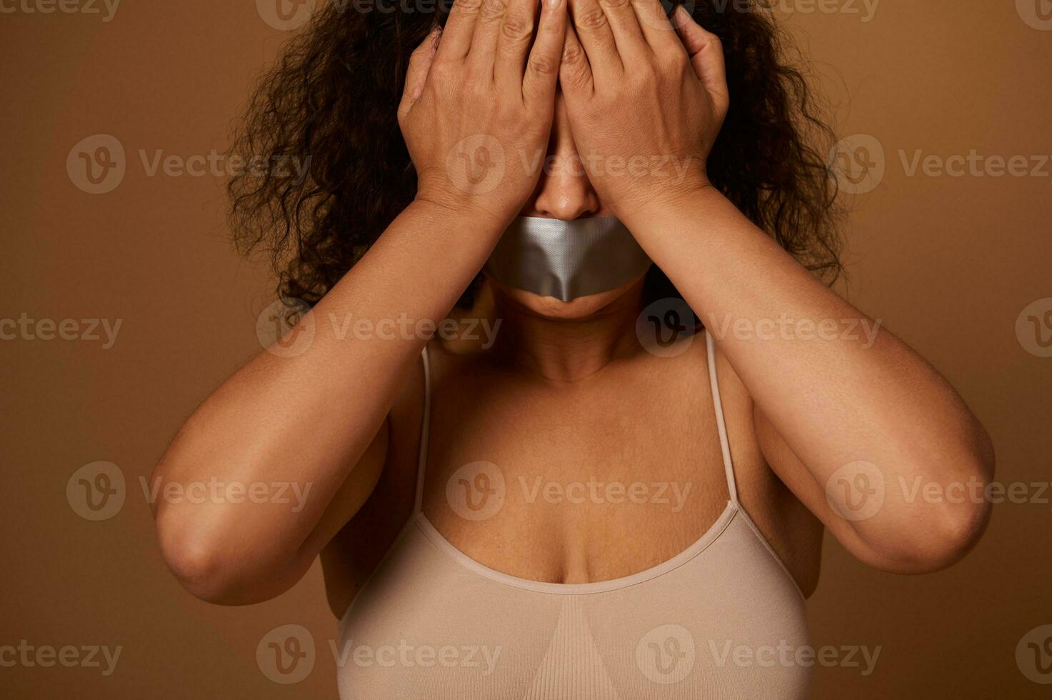 social concept pour portion à bats toi et éliminer agression et la violence contre femmes. effrayé femme avec scellé bouche couvrant sa yeux avec mains, isolé sur foncé beige Contexte avec copie espace photo