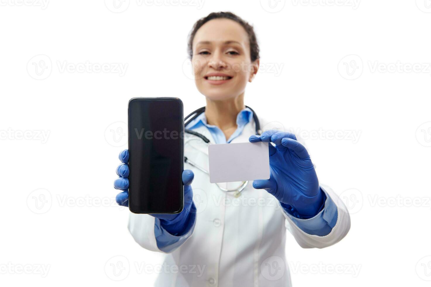 flou souriant médecin en portant mobile téléphone et Plastique carte et montrant leur à le caméra. isolé blanc Contexte. santé Assurance concept photo