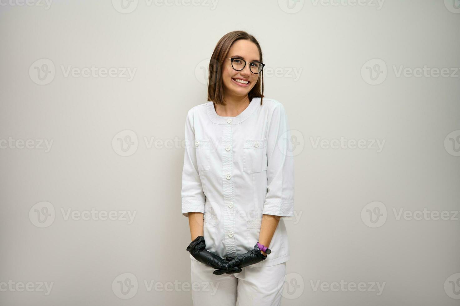 concentrer sur faciale expressions de une magnifique femelle médecin interne, médical, santé se soucier ouvrier dans blanc médical uniforme, souriant à pleines dents sourire posant contre blanc mur Contexte avec copie espace photo