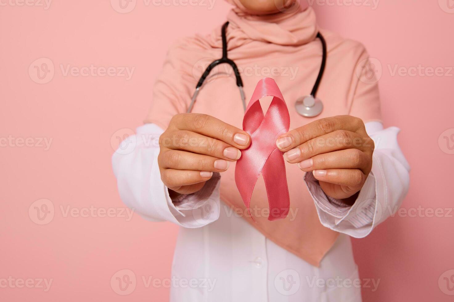 fermer de main de médecin dans rose hijab, en portant rose ruban. monde cancer journée. Sein et abdominal cancer conscience, octobre rose jour, coloré arrière-plan, copie espace. Sein cancer soutien concept. photo