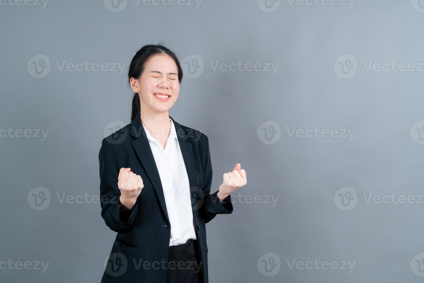 femme asiatique se réjouissant de son succès et de sa victoire en serrant les poings de joie. femme chanceuse étant heureuse d'atteindre son but et ses objectifs. émotions positives, sentiments. photo