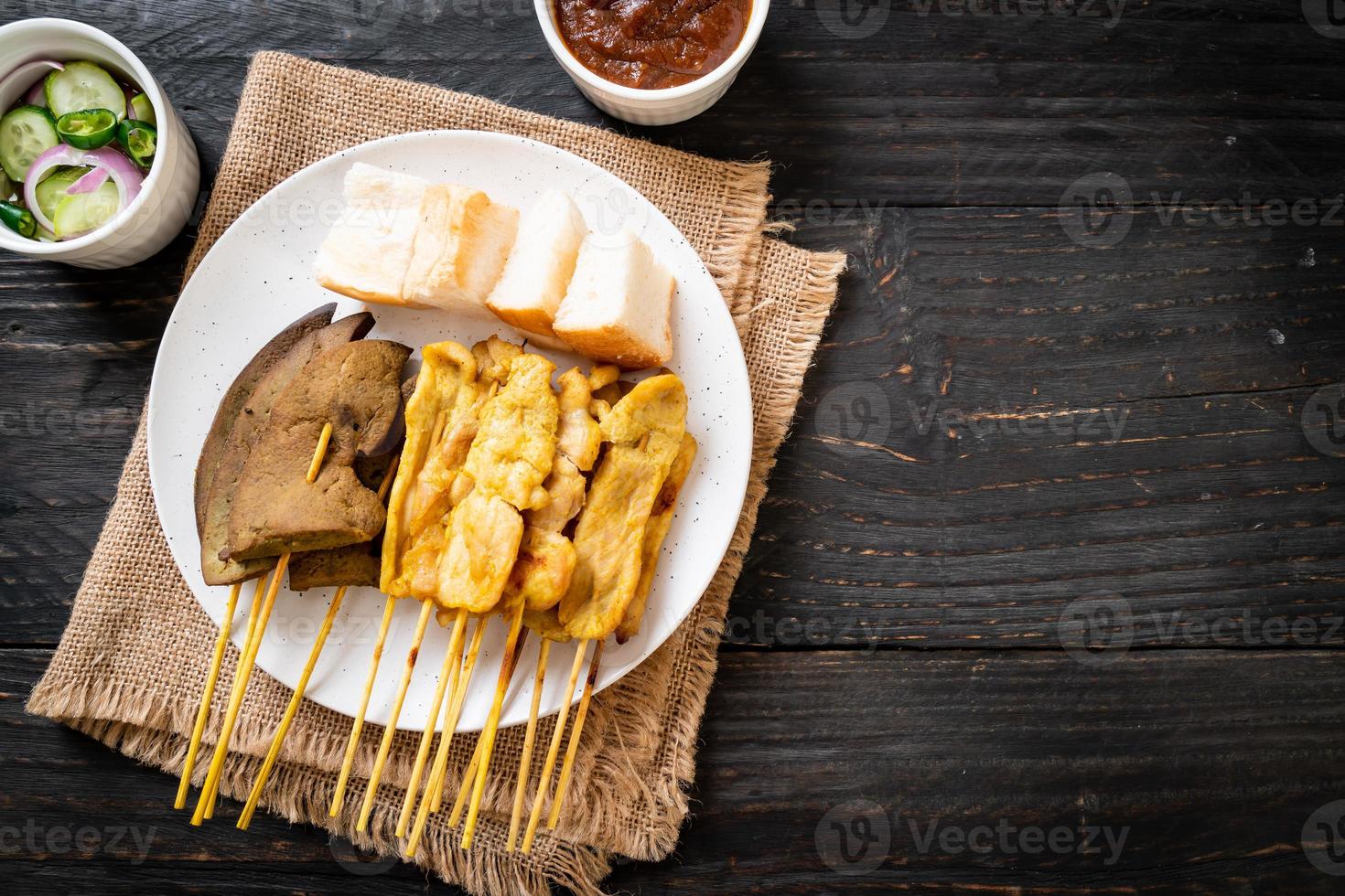 satay de porc avec votre sauce aux cacahuètes et cornichons qui sont des tranches de concombre et des oignons au vinaigre photo