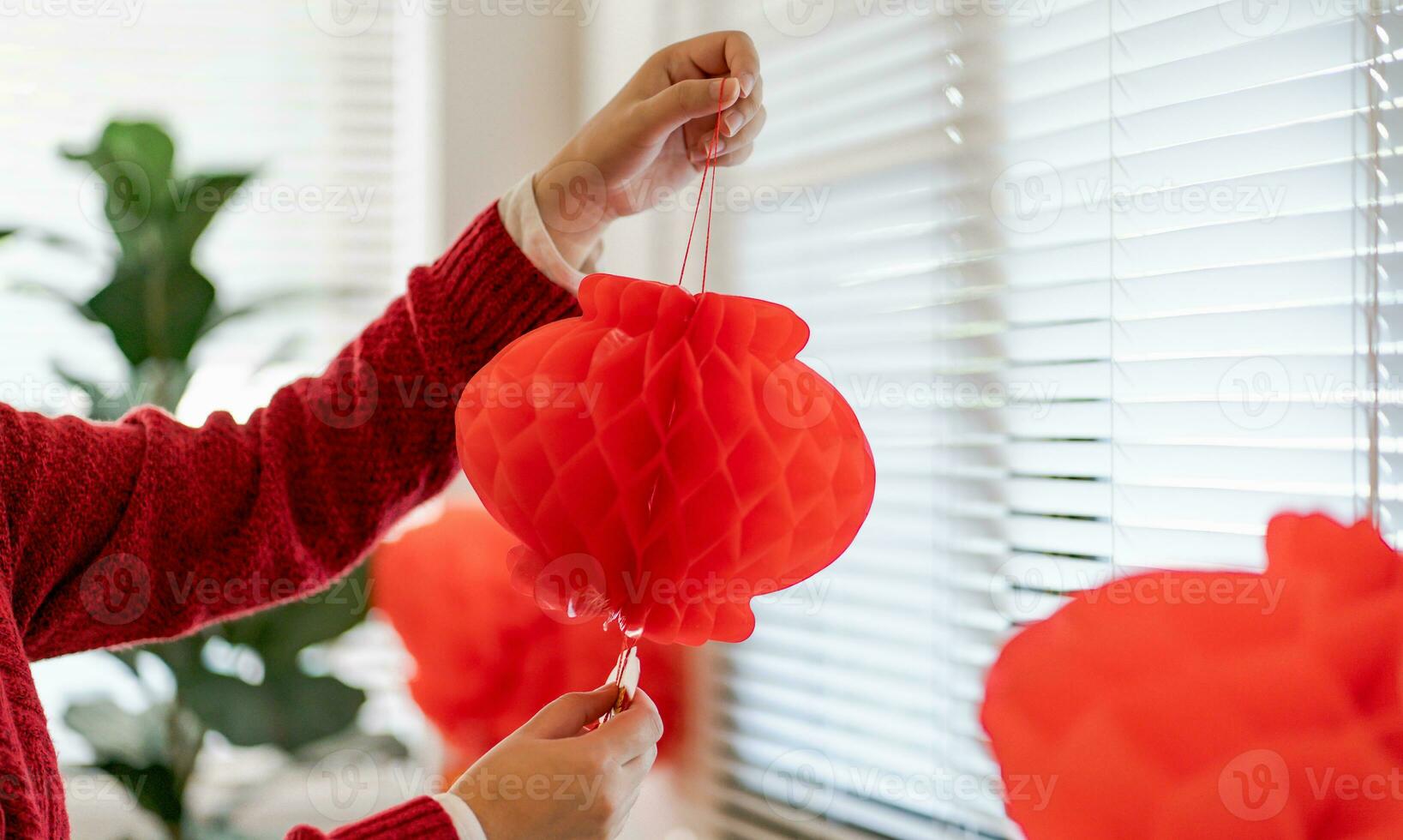 asiatique femme en portant rouge chinois Nouveau année lanterne tandis que décoré plat en mettant traditionnel pendentif à le chinois Nouveau année célébrations pour bien chance. chinois mot veux dire bénédiction. photo