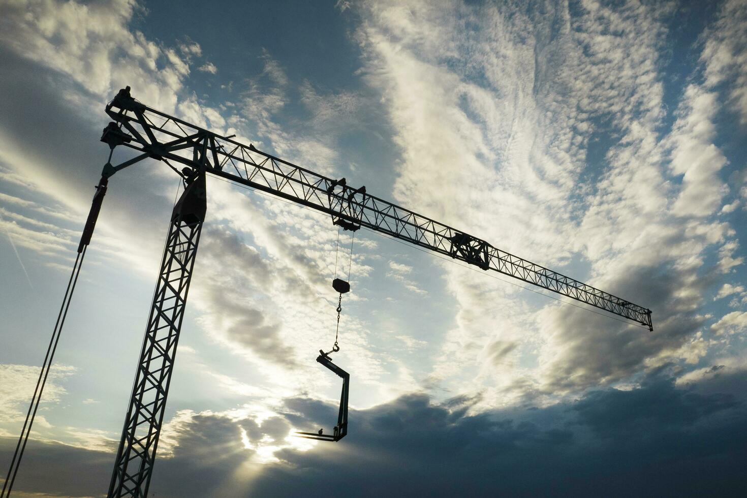 le profil de une construction grue à le coucher du soleil photo