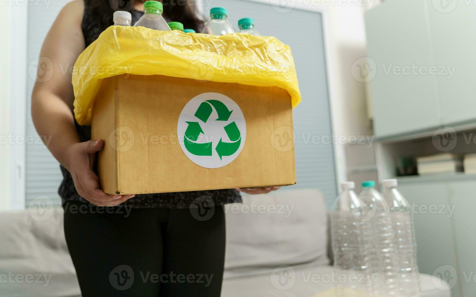 Accueil recycler éco vert zéro concept femme lancement vide Plastique bouteille dans recyclage poubelle avec Jaune des ordures Sacs à maison. photo