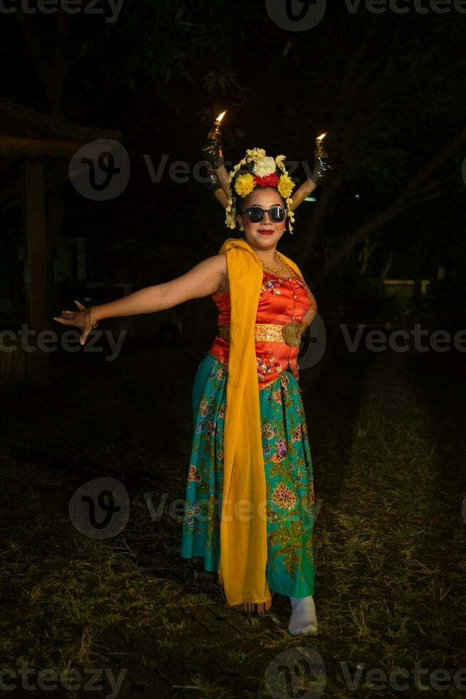 une traditionnel Javanais Danseur des stands et danses avec une souple corps tandis que portant des lunettes de soleil photo