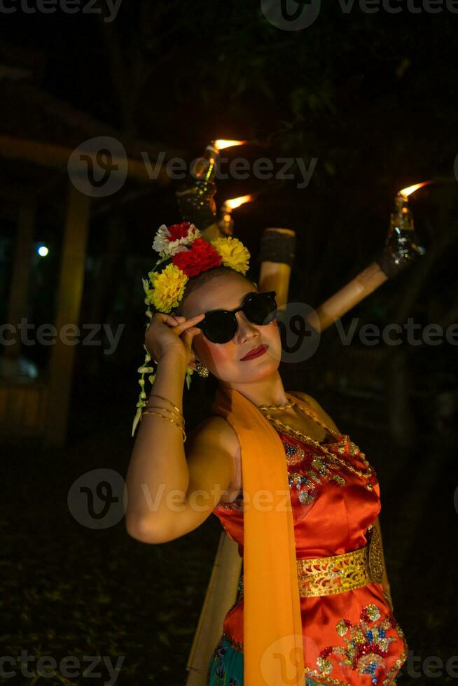 une traditionnel asiatique Danseur pose avec des lunettes de soleil tandis que dansant sur étape photo