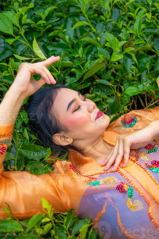 un asiatique femme en train de dormir sur vert thé feuilles photo