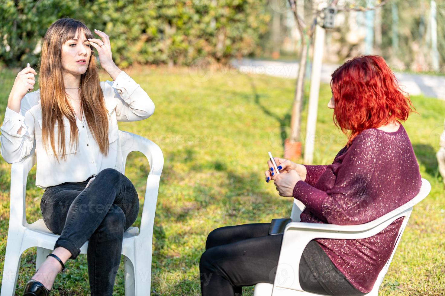 filles fumant une cigarette électronique dans le jardin photo