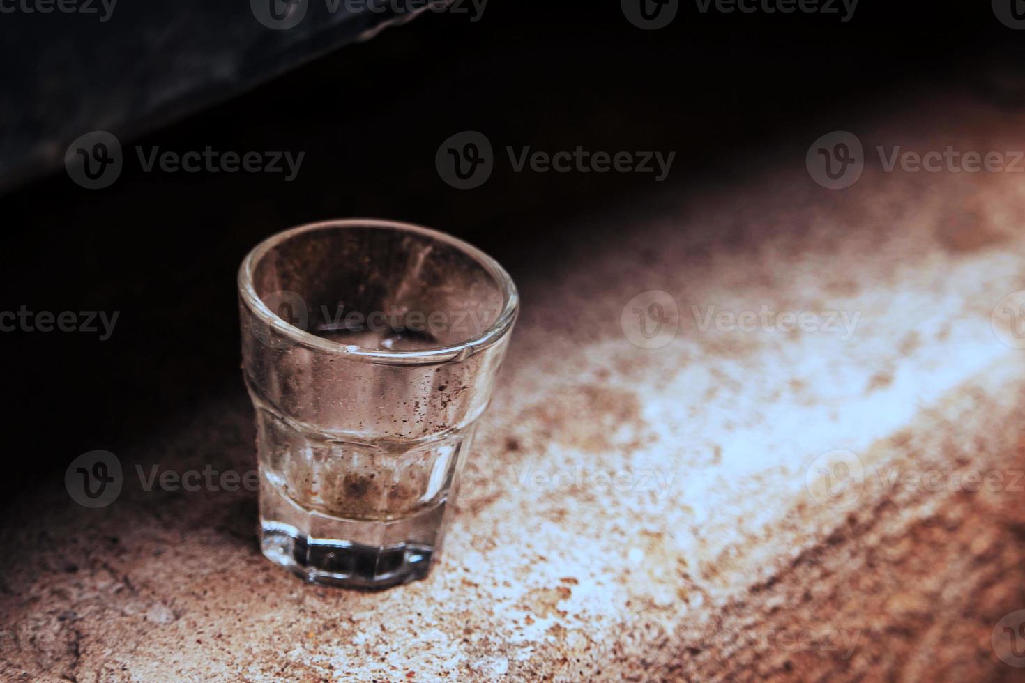 petit verre vide debout seul sur une surface en béton photo