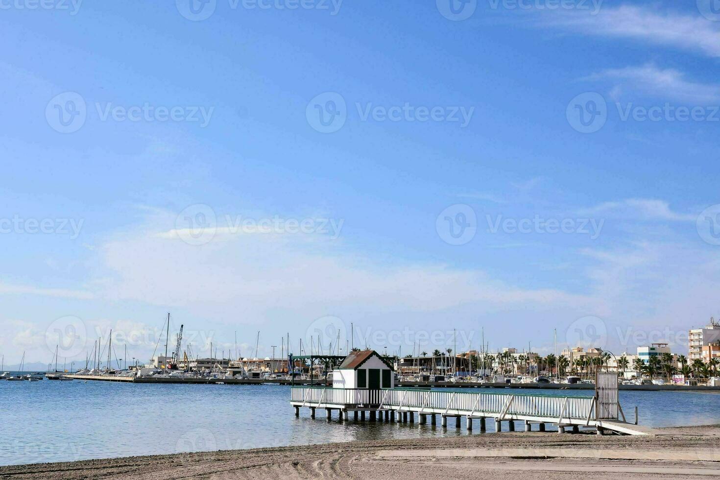 une jetée avec bateaux sur le l'eau et une plage photo
