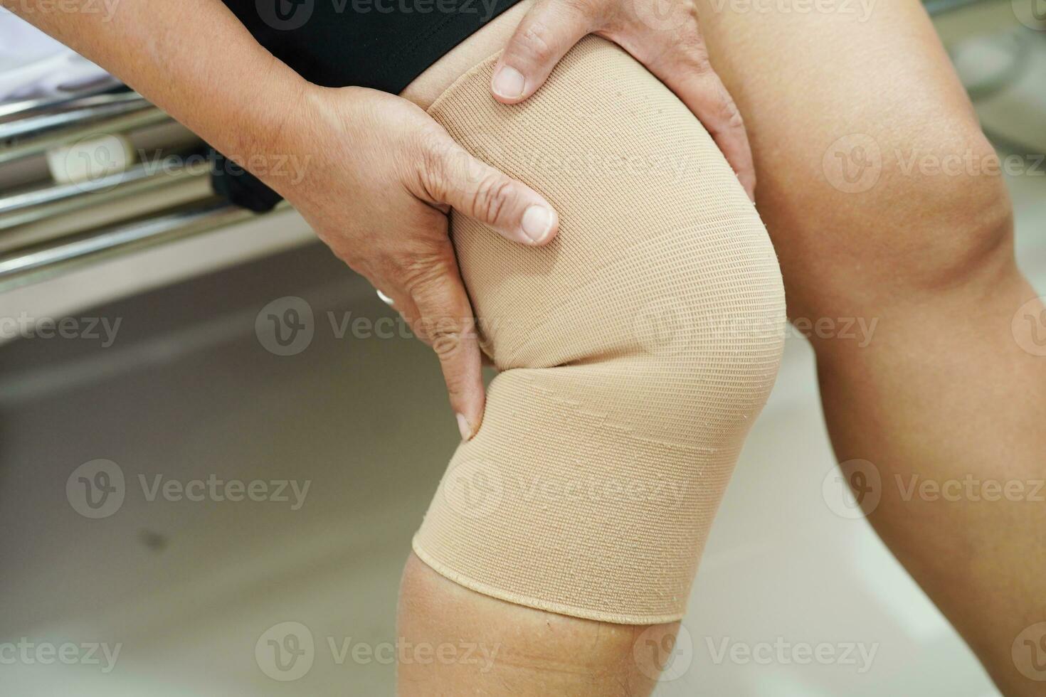 femme senior asiatique portant une genouillère à support élastique pour réduire la douleur. photo